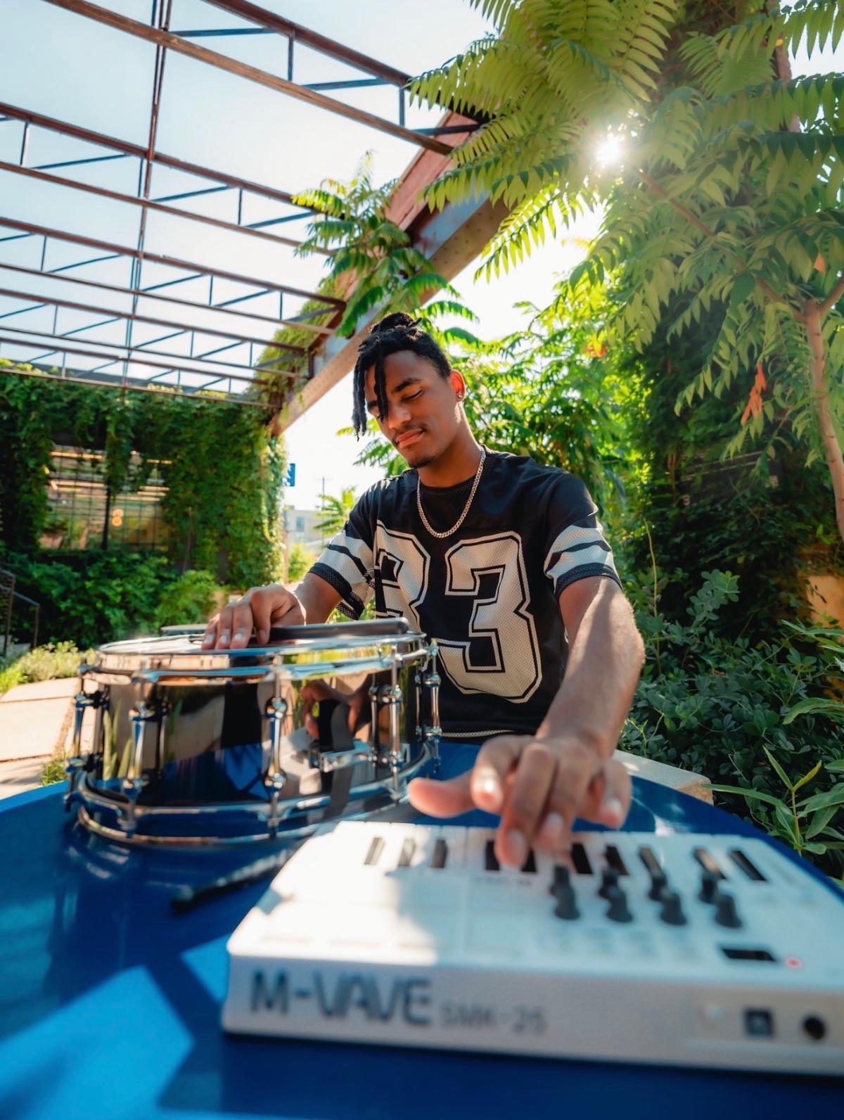 Jaywill Williams playing a snare drum and MIDI keyboard outdoors under warm sunlight in Charlotte, NC