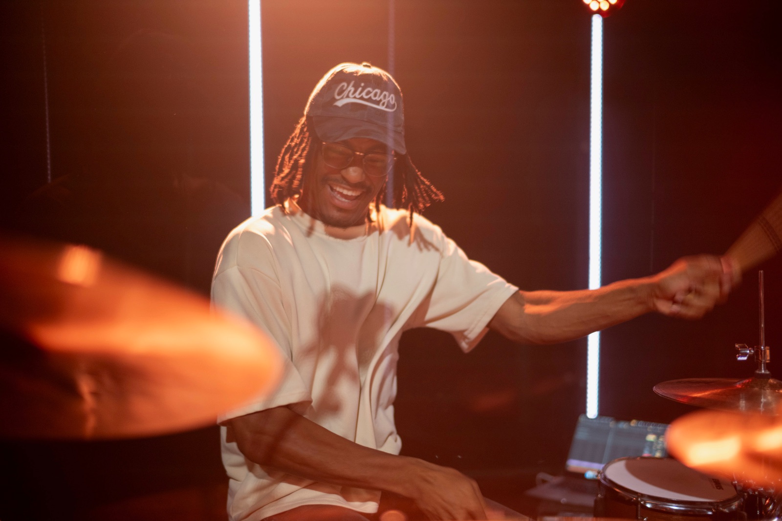Jaywill smiling behind the kit under warm stage light